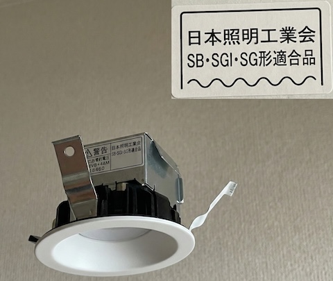 ダウンライトの外観写真と、拡大されたラベルの図。ラベルには「日本照明工業会 SB・SGI・SG形適合品」と書かれている
